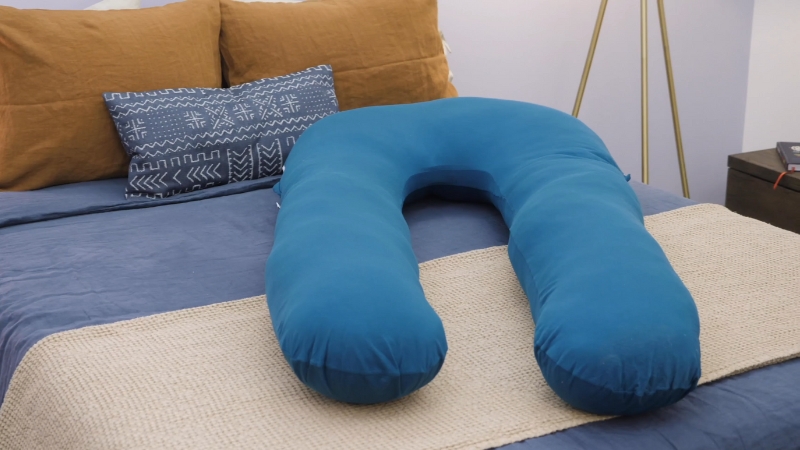 Plavi trudnički jastuk u obliku slova U na krevetu